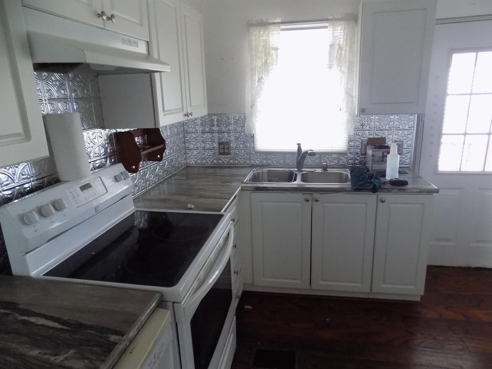 A kitchen features white cabinets, a glass-top stove, a double sink, and metallic backsplash tiles — 18009 Huapi, Boynton Beach FL 33436, BOYNTON BEACH, FL