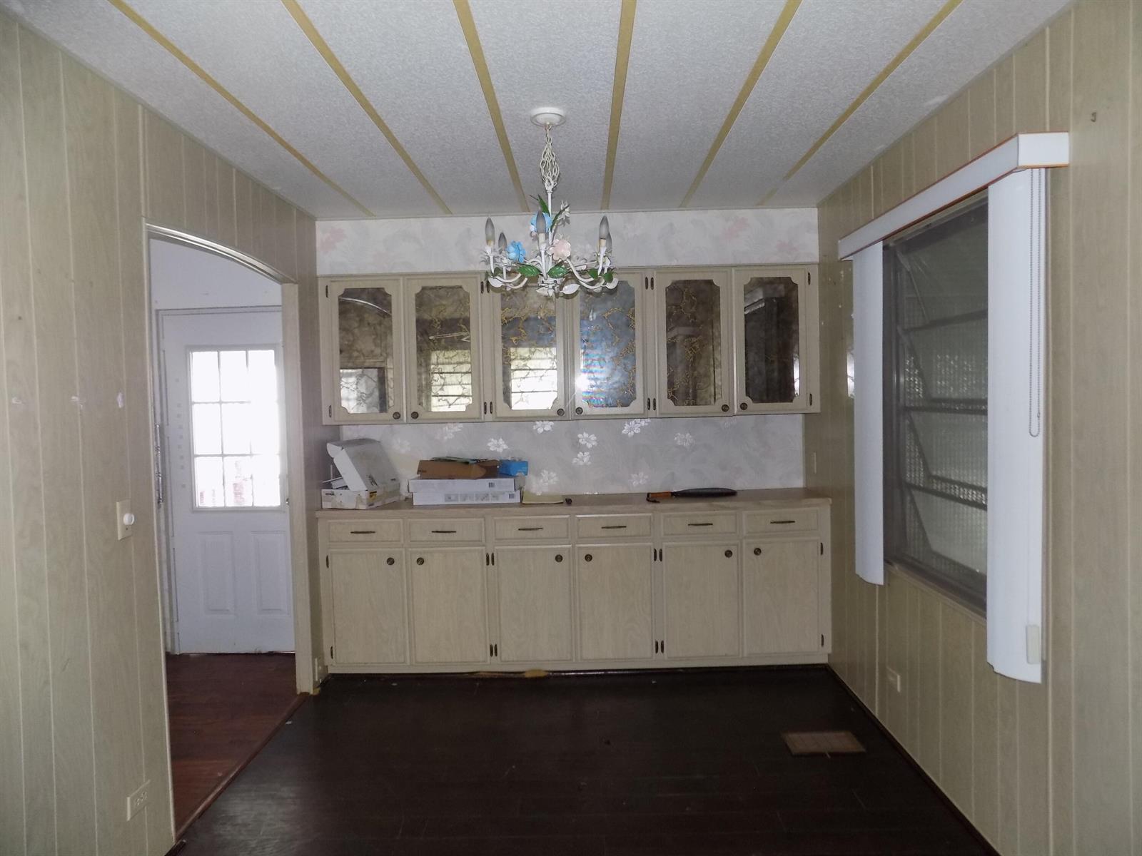 A dining area features wood-paneled walls, dark flooring, built-in cabinetry, and a floral chandelier — 18009 Huapi, Boynton Beach FL 33436, BOYNTON BEACH, FL