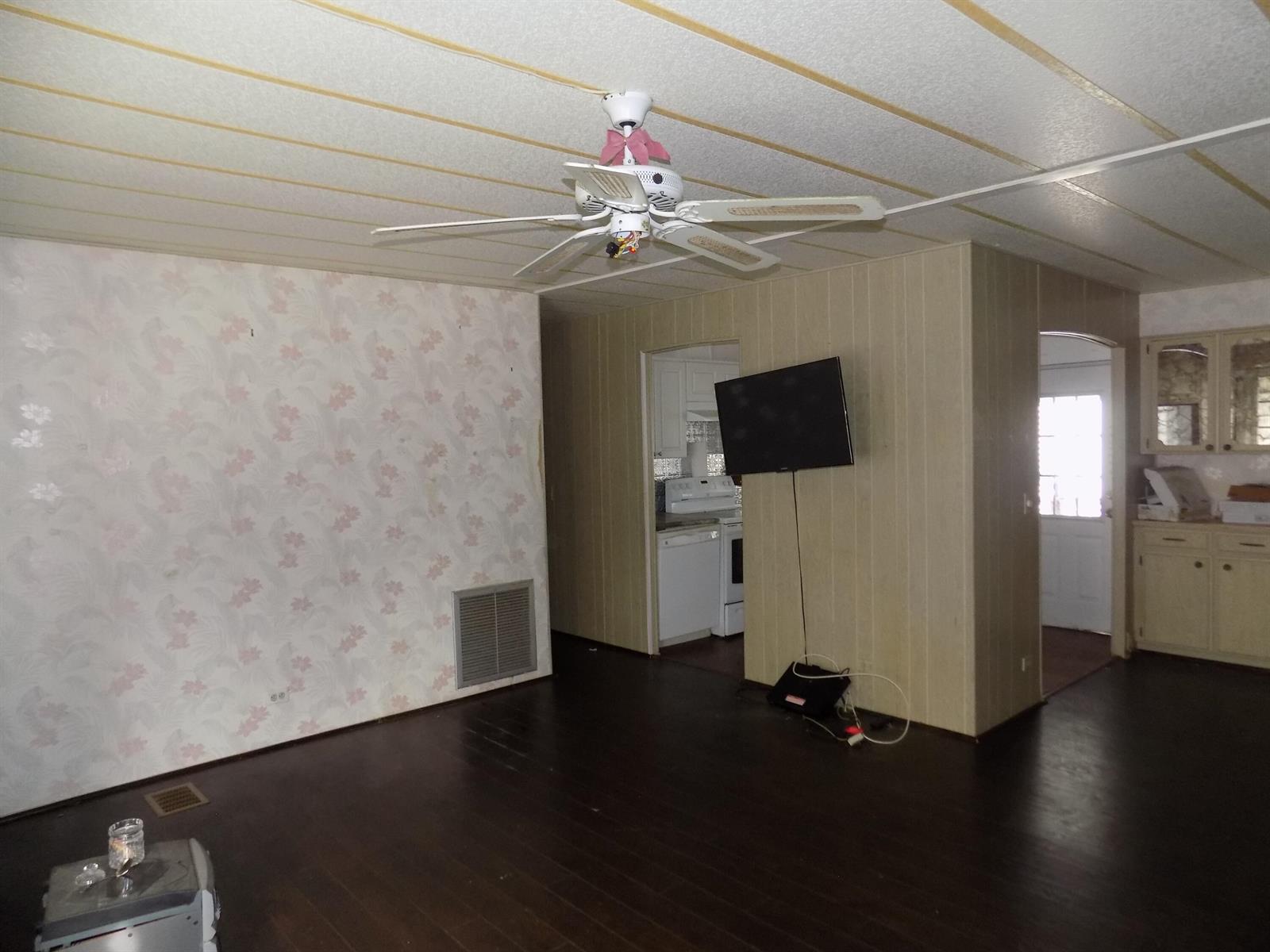 A living room with dark wood flooring, floral wallpaper, a ceiling fan, and wall-mounted television — 18009 Huapi, Boynton Beach FL 33436, BOYNTON BEACH, FL