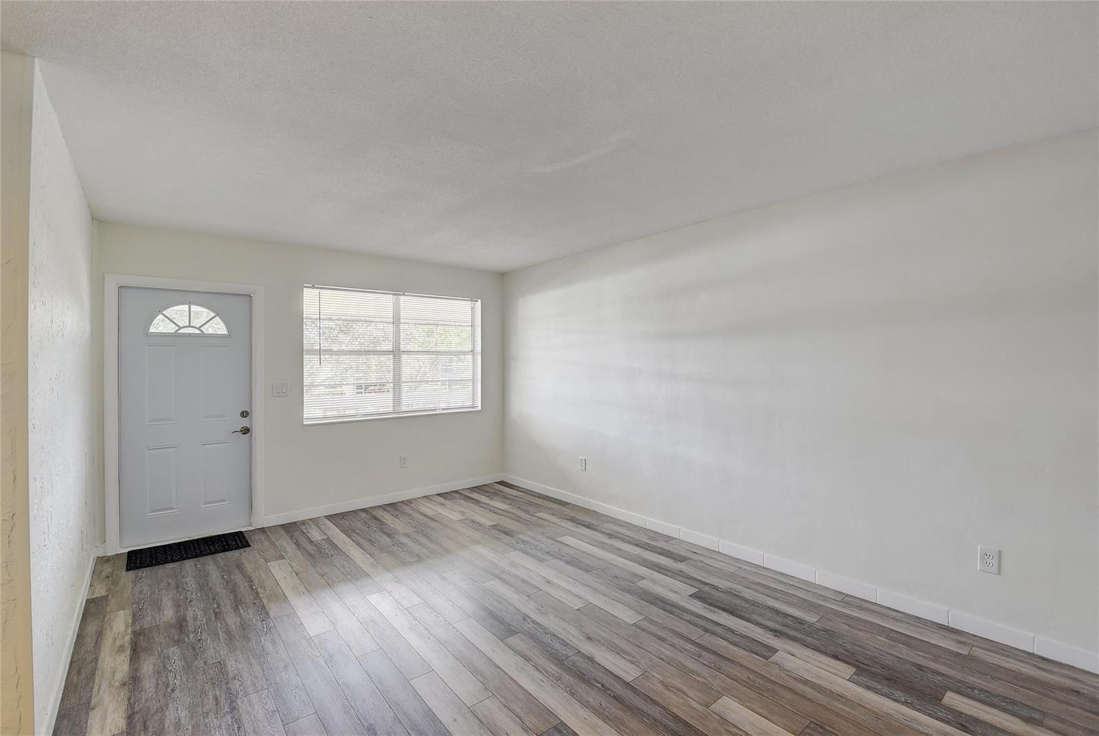 An empty room features white walls, a front door, a window, and wood-look flooring — 30 SE 13th Street # B2, Boca Raton FL 33432, BOCA RATON, FL