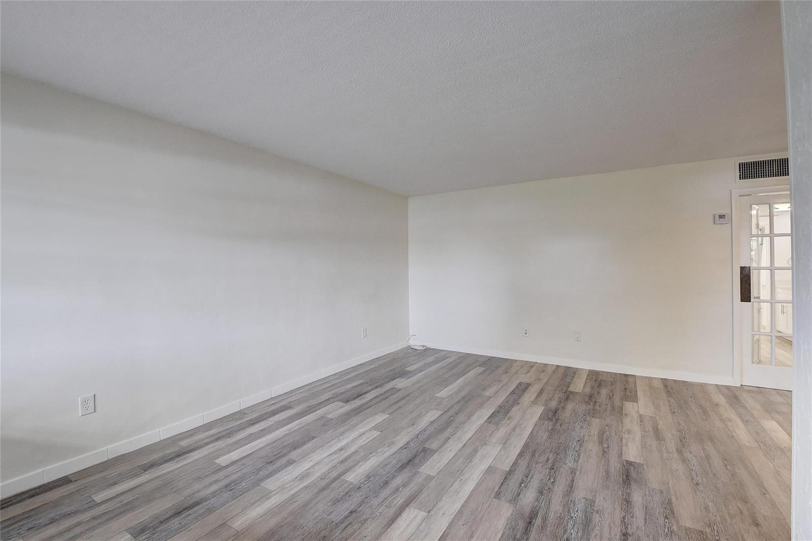 An empty room features white walls, a textured ceiling, and light-colored wood-look plank flooring — 30 SE 13th Street # B2, Boca Raton FL 33432, BOCA RATON, FL