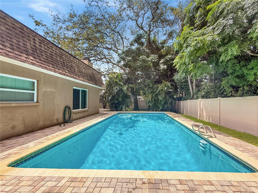 A tan stucco house exterior features a red front door and a large window — 1011 WINDING OAKS DRIVE, PALM HARBOR, FL
