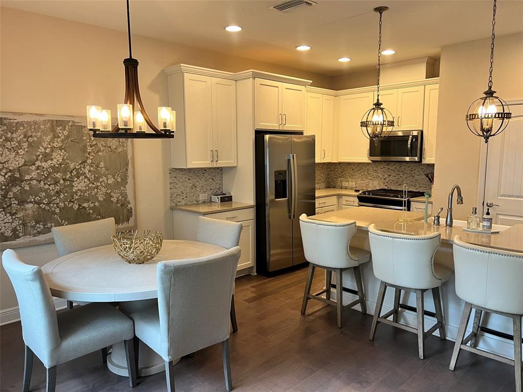 A kitchen and dining area featuring white cabinets, stainless steel appliances, and pendant lighting — 115 N ARRAWANA AVENUE UNIT 7, TAMPA, FL