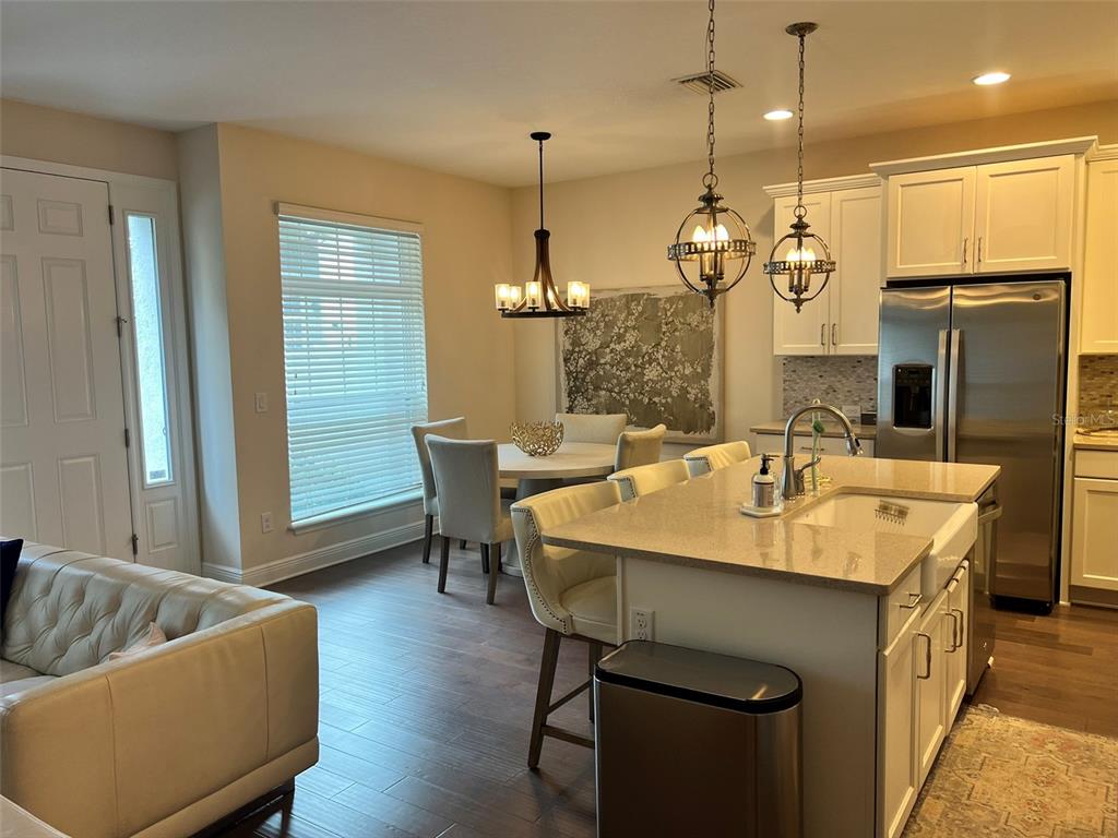 A kitchen with a center island, dining area, and light-colored cabinetry on a wood floor — 115 N ARRAWANA AVENUE UNIT 7, TAMPA, FL