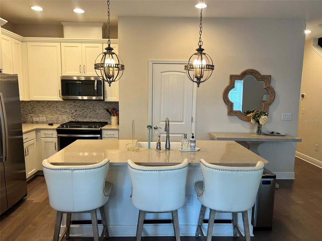 A kitchen island with three white stools sits in front of white cabinets and appliances — 115 N ARRAWANA AVENUE UNIT 7, TAMPA, FL