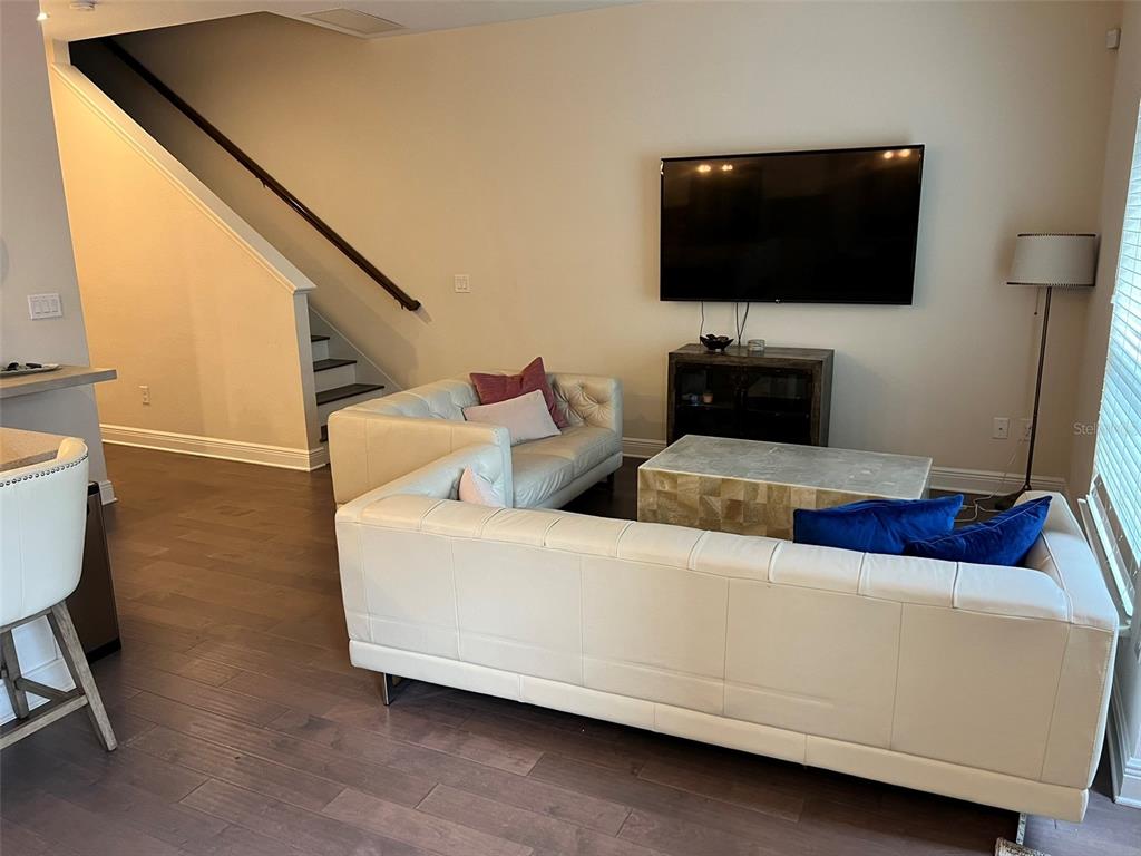 A living room features a white sectional sofa, a coffee table, and a wall-mounted television — 115 N ARRAWANA AVENUE UNIT 7, TAMPA, FL