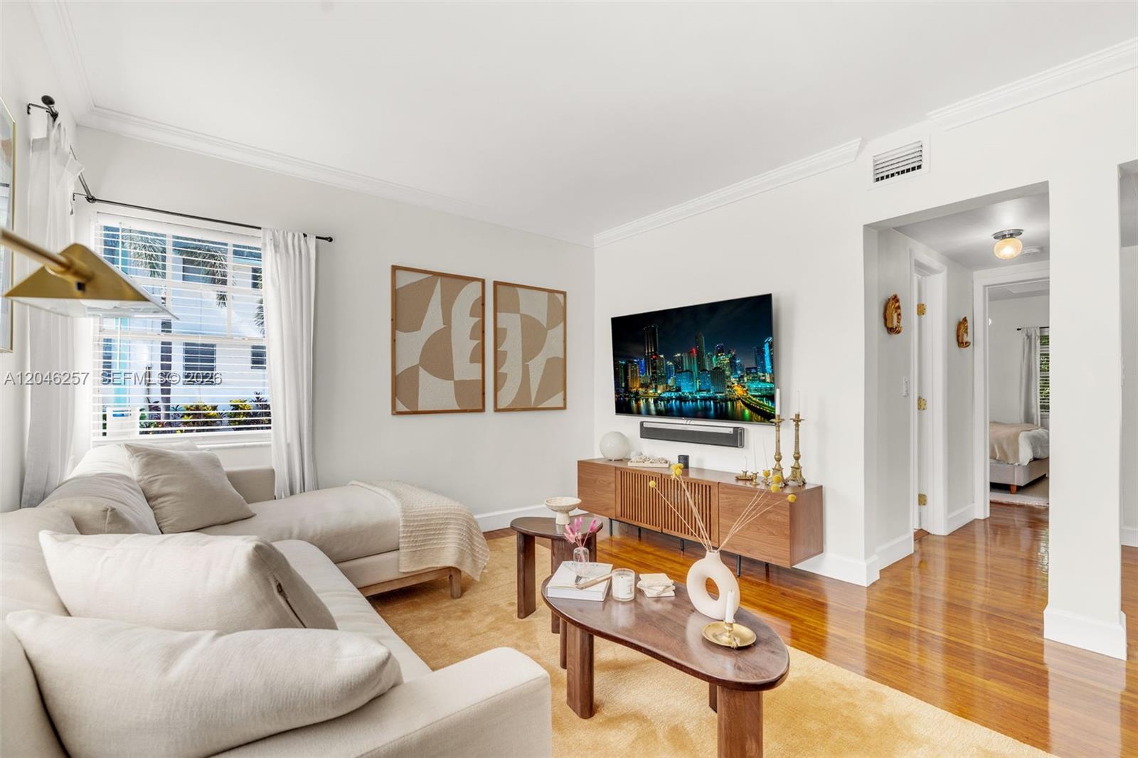 A living room features a beige sectional sofa, a wooden media console, and hardwood floors — 915 8th St # 101, Miami Beach FL 33139, MIAMI BEACH, FL
