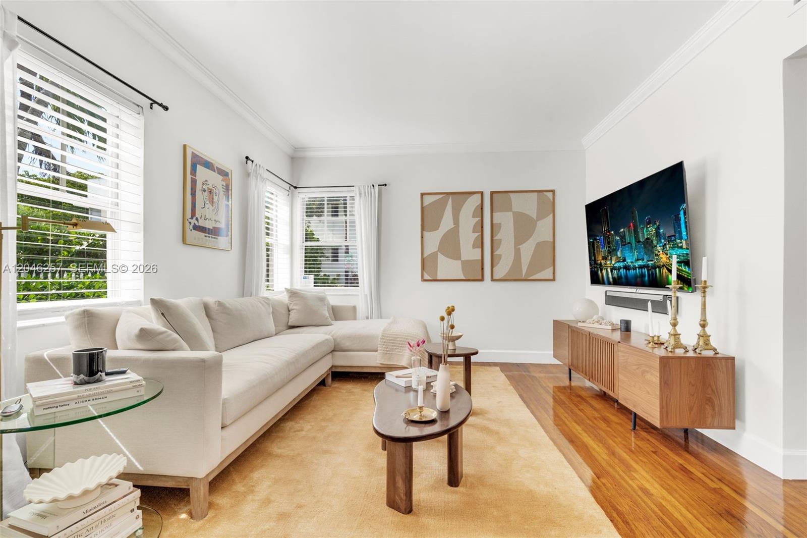 A living room features a cream sectional sofa, wooden coffee tables, and a wall-mounted television — 915 8th St # 101, Miami Beach FL 33139, MIAMI BEACH, FL