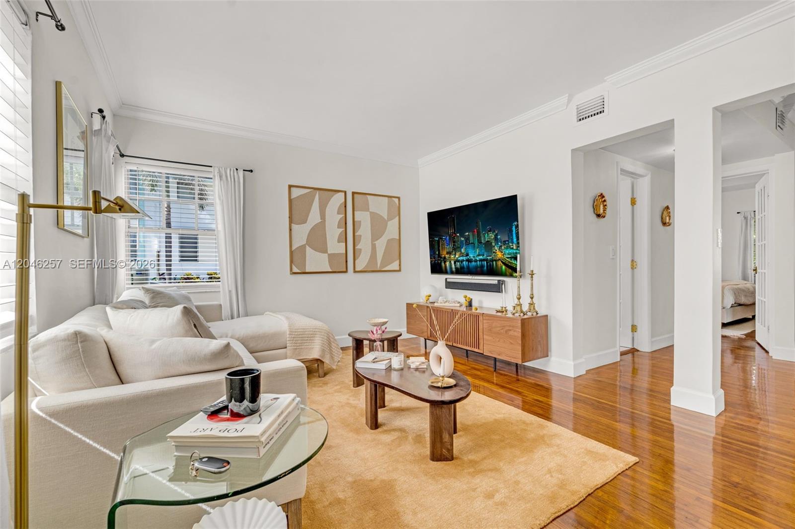 A living room features a beige sectional sofa, a wooden media console, and hardwood floors — 915 8th St # 101, Miami Beach FL 33139, MIAMI BEACH, FL