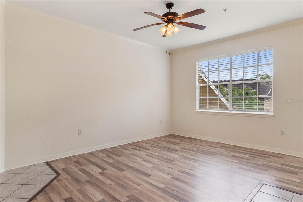 An empty room with light-colored walls, wood-look flooring, a ceiling fan, and a large window — 2558 ROBERT TRENT JONES DRIVE UNIT 1434, ORLANDO, FL