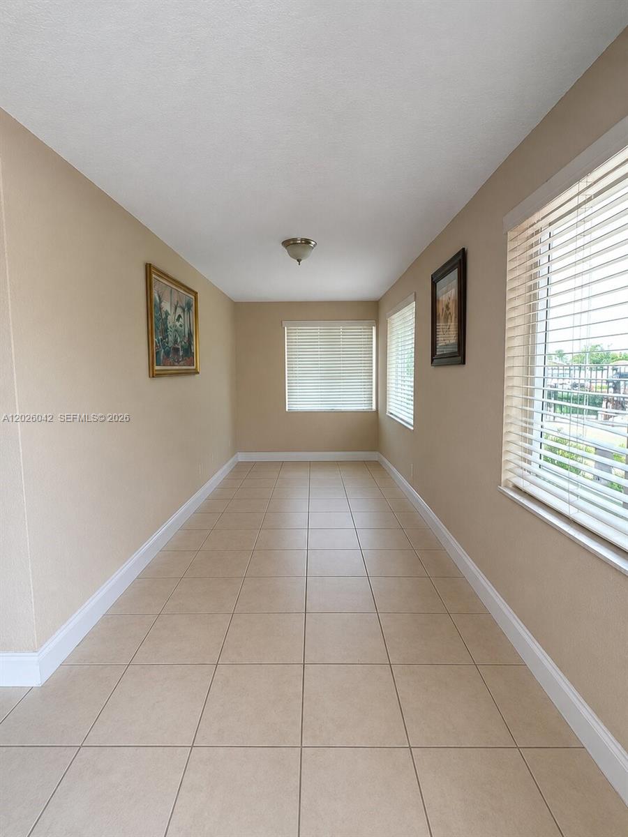 This narrow, tiled room features beige walls, a ceiling light, and multiple windows with blinds — 5551 E 4th Ave, Hialeah FL 33013, HIALEAH, FL