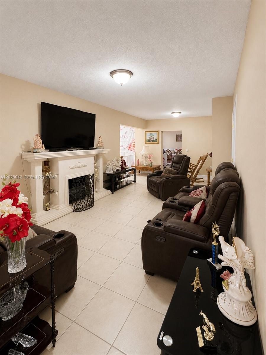 A living room features a fireplace, a wall-mounted television, and brown leather reclining furniture — 5551 E 4th Ave, Hialeah FL 33013, HIALEAH, FL