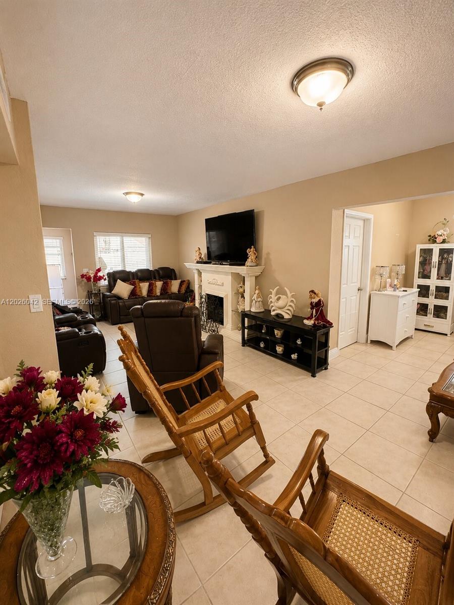 A living room features tile flooring, a fireplace with a television, and wooden rocking chairs — 5551 E 4th Ave, Hialeah FL 33013, HIALEAH, FL