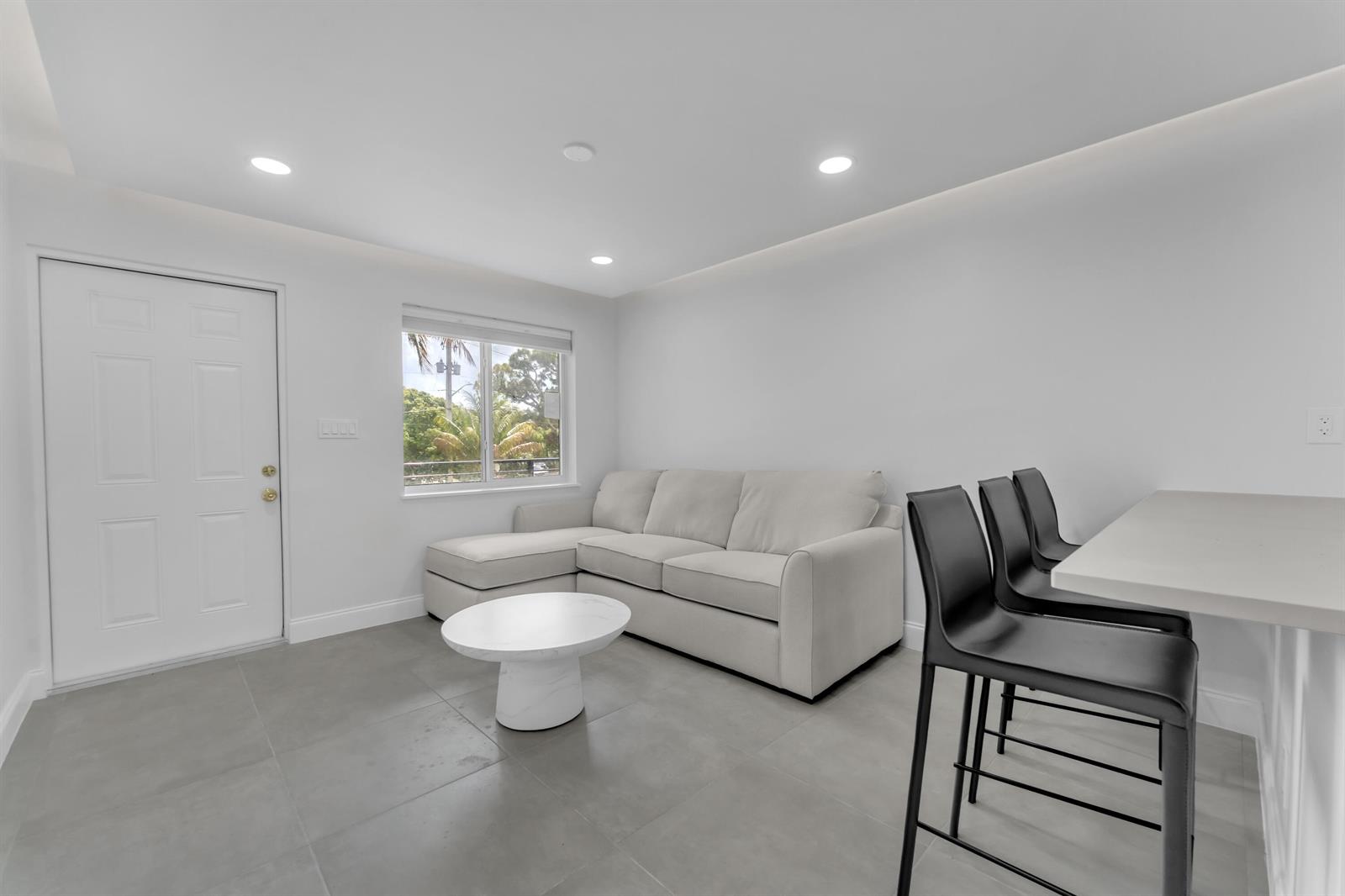 A living room with gray tile floors, a white sectional sofa, and a breakfast bar — 381 SE 15th Avenue # 1, Deerfield Beach FL 33441, DEERFIELD BEACH, FL