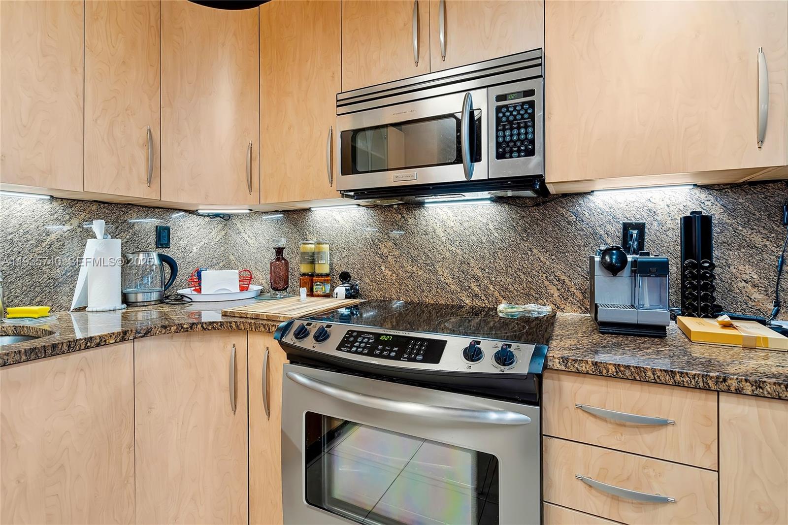 A kitchen features light wood cabinets, stainless steel appliances, and a dark granite countertop — 1400 S Ocean Dr # 802, Hollywood FL 33019, HOLLYWOOD, FL