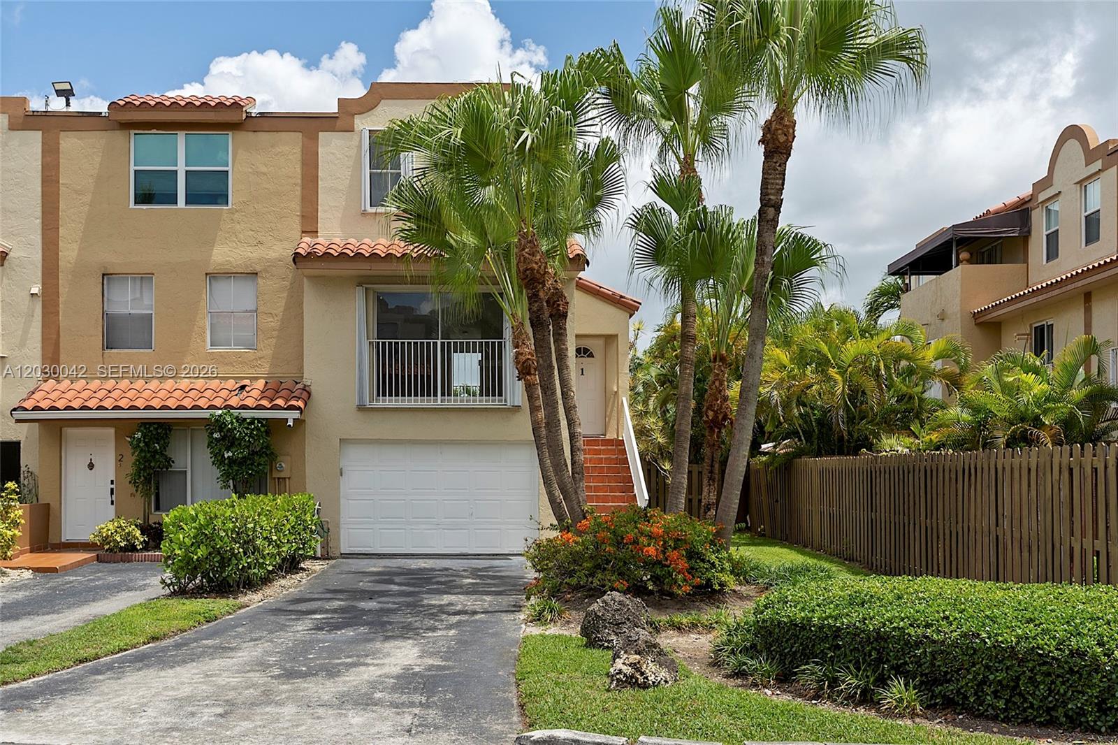 The exterior of a multi-story townhouse features a garage, a balcony, and palm trees — 8631 NW 4th Ter # 1001, Miami FL 33126, MIAMI, FL