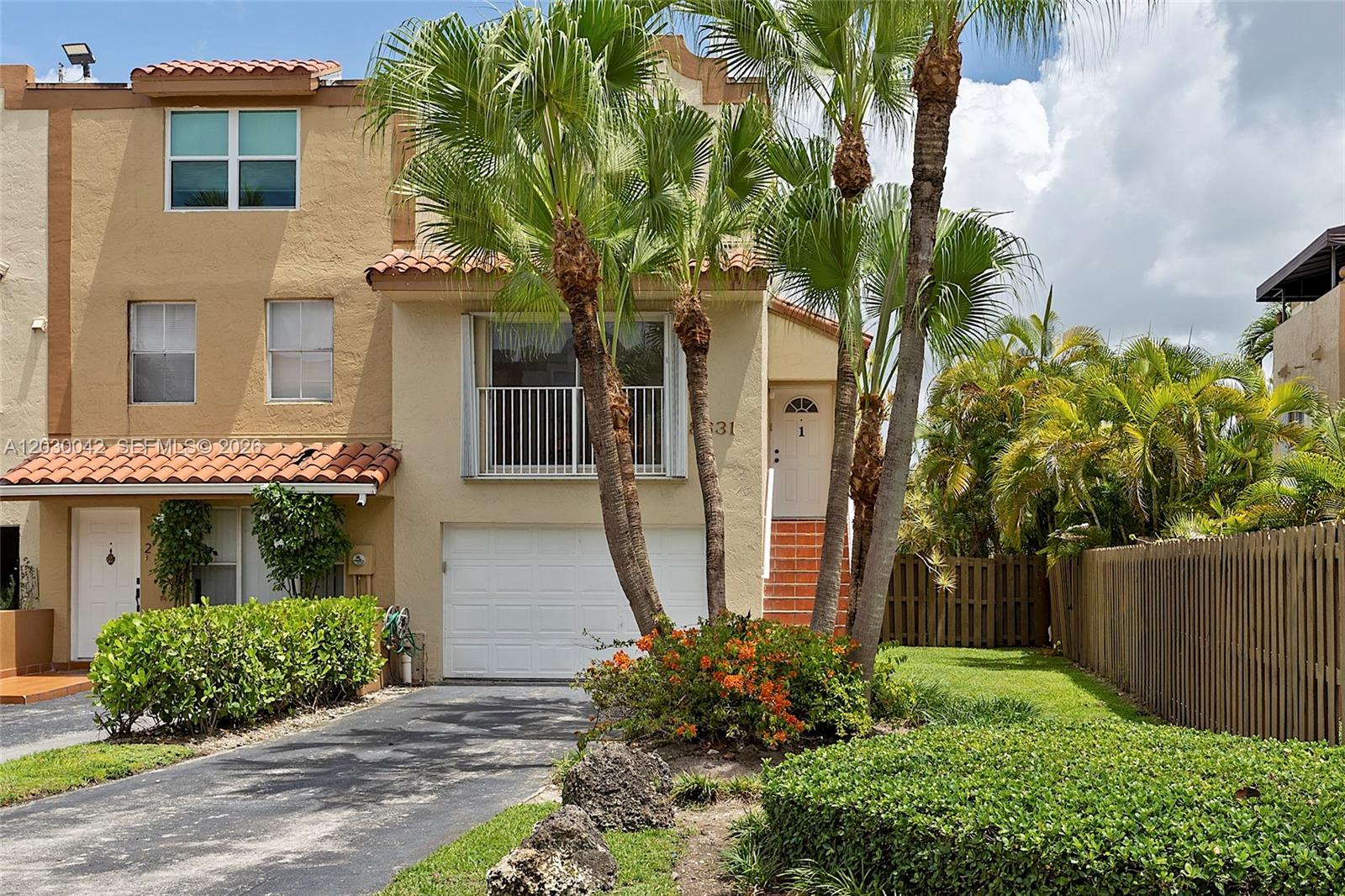 A tan two-story townhouse features a white garage door, a balcony, and palm trees — 8631 NW 4th Ter # 1001, Miami FL 33126, MIAMI, FL
