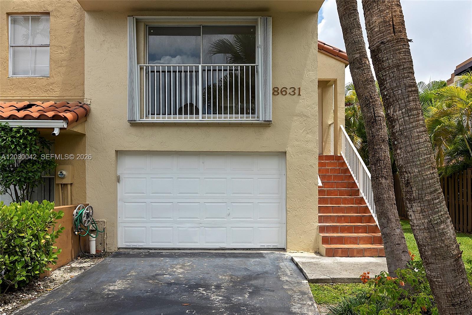The exterior of a two-story townhouse features a white garage door and an outdoor staircase — 8631 NW 4th Ter # 1001, Miami FL 33126, MIAMI, FL
