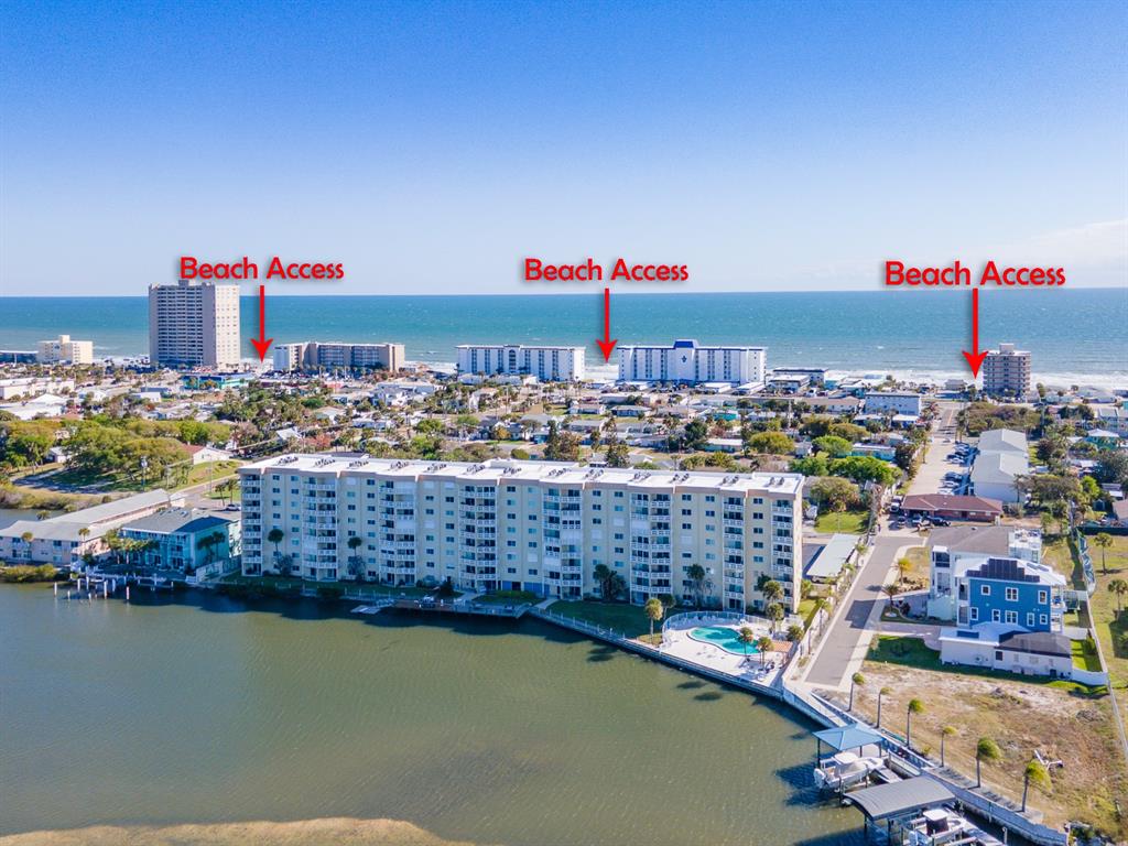 An aerial view shows a multi-story apartment building near a body of water and beach — 3606 S PENINSULA DRIVE UNIT 605, PORT ORANGE, FL