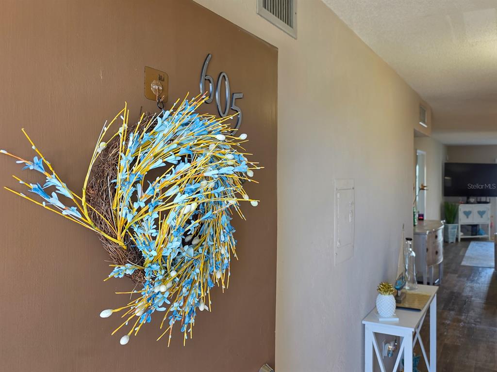 A brown door with a blue and yellow wreath is labeled with the number 605 — 3606 S PENINSULA DRIVE UNIT 605, PORT ORANGE, FL