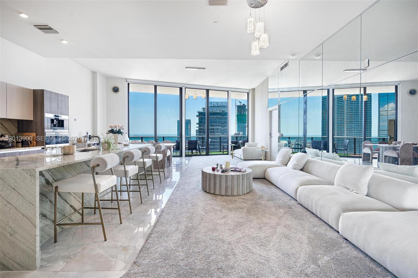 A modern open-concept living area features a kitchen island, white sectional sofa, and floor-to-ceiling windows — 801 S Miami Ave # 5702, Miami FL 33130, MIAMI, FL