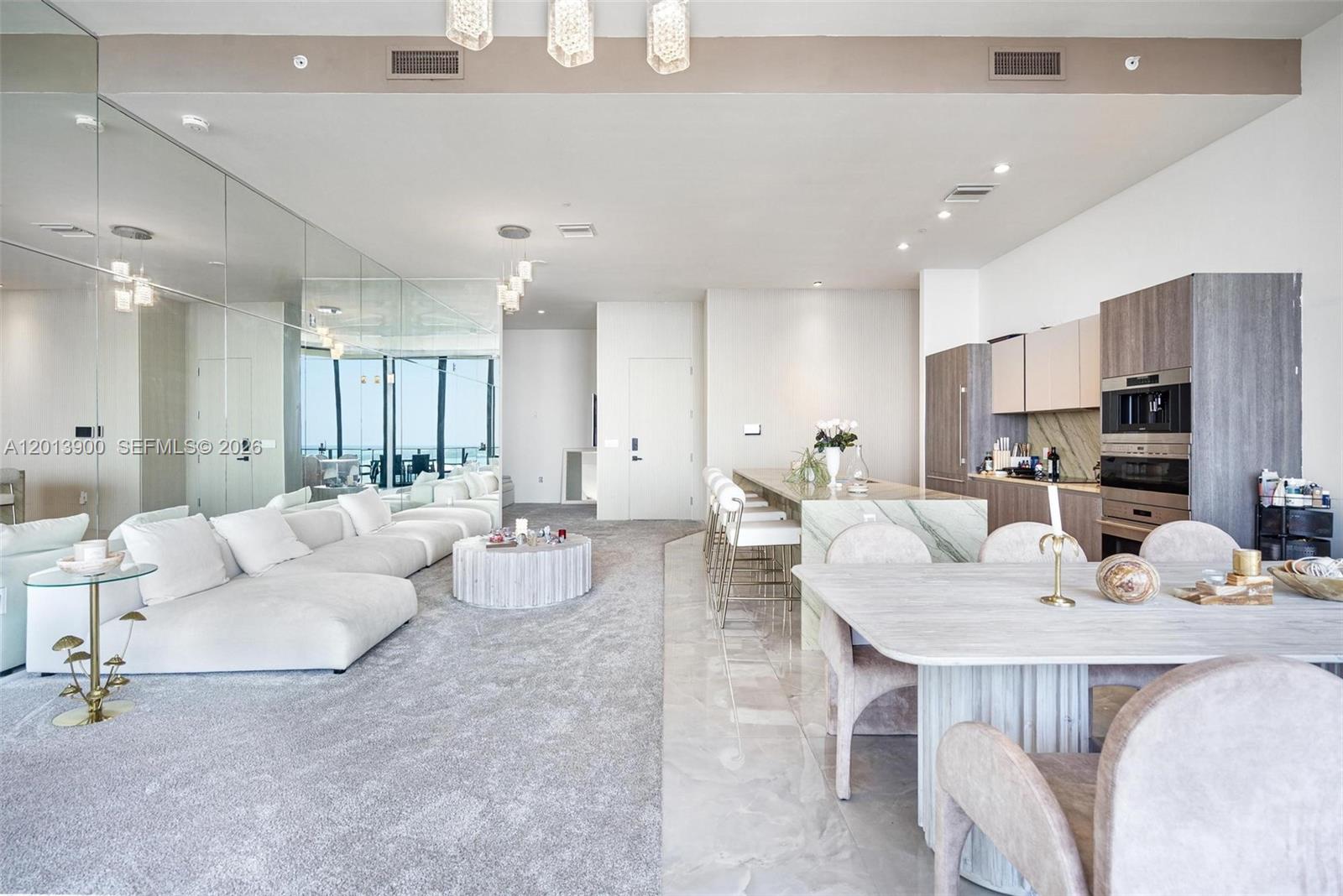 An open-concept living and dining area features a mirrored wall, carpeted flooring, and kitchen island — 801 S Miami Ave # 5702, Miami FL 33130, MIAMI, FL