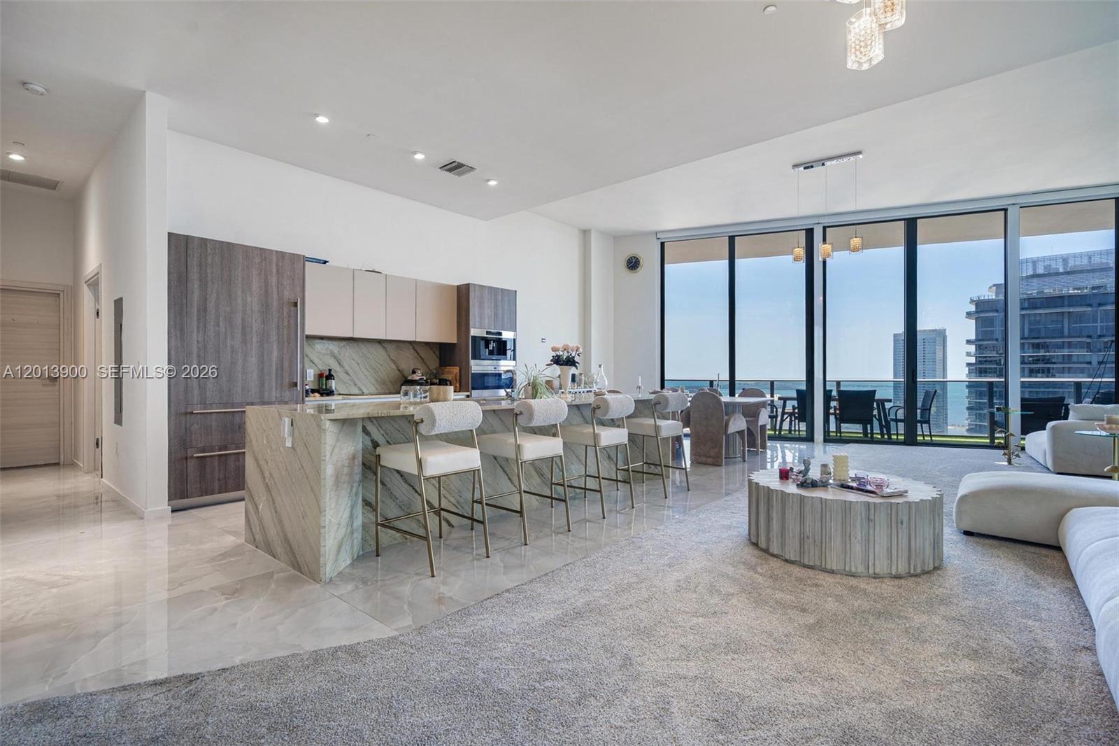 A modern open-concept kitchen and living area features a marble island and floor-to-ceiling windows — 801 S Miami Ave # 5702, Miami FL 33130, MIAMI, FL