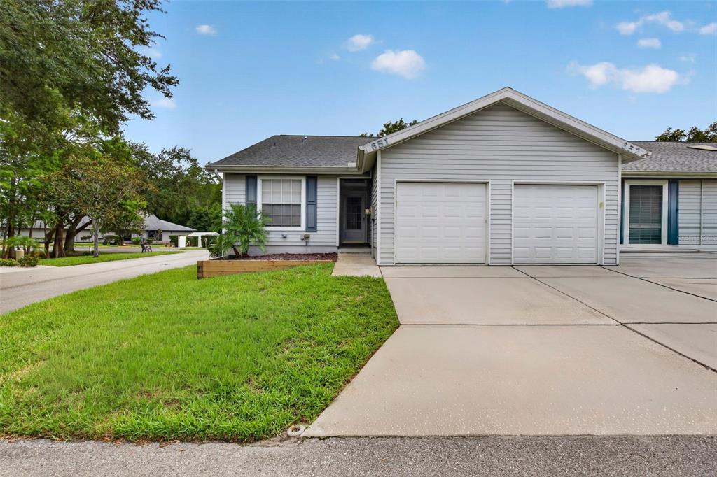 A single-story duplex with light gray siding, two garage doors, and a concrete driveway — 39650 US HIGHWAY 19 N UNIT 651, TARPON SPRINGS, FL