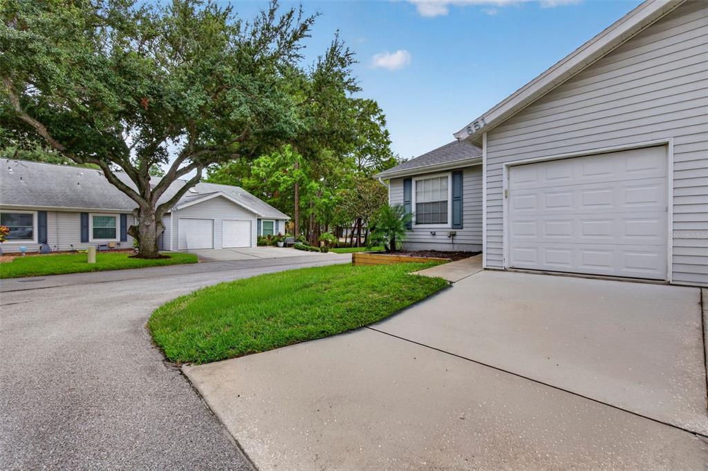A view of a residential street featuring two single-story houses with garages and driveways — 39650 US HIGHWAY 19 N UNIT 651, TARPON SPRINGS, FL