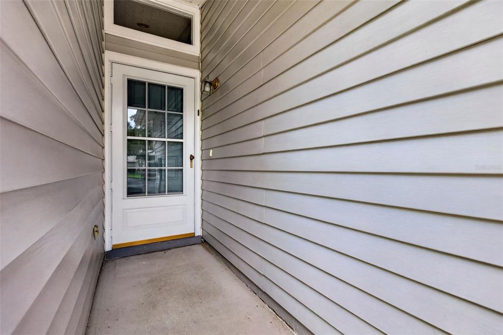 A white door with glass panels is set into a gray vinyl-sided exterior entryway — 39650 US HIGHWAY 19 N UNIT 651, TARPON SPRINGS, FL