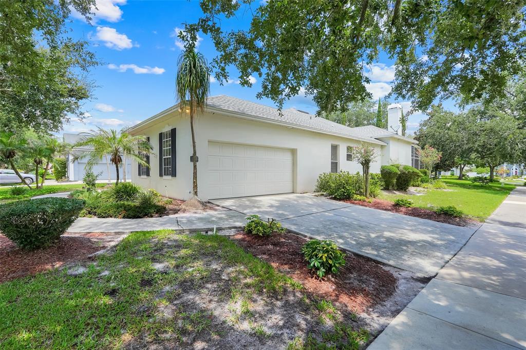 A white single-story house with a two-car garage and a concrete driveway — 8003 BELSHIRE DRIVE, ORLANDO, FL