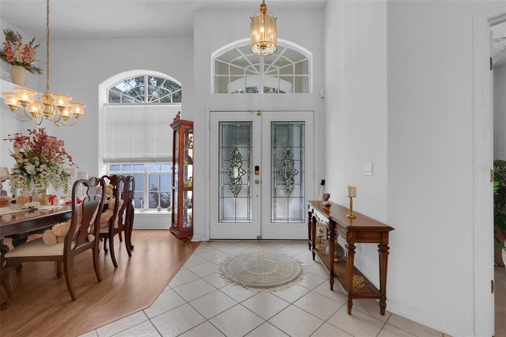 A tiled foyer features a double front door with glass inserts and a wooden console table — 8003 BELSHIRE DRIVE, ORLANDO, FL