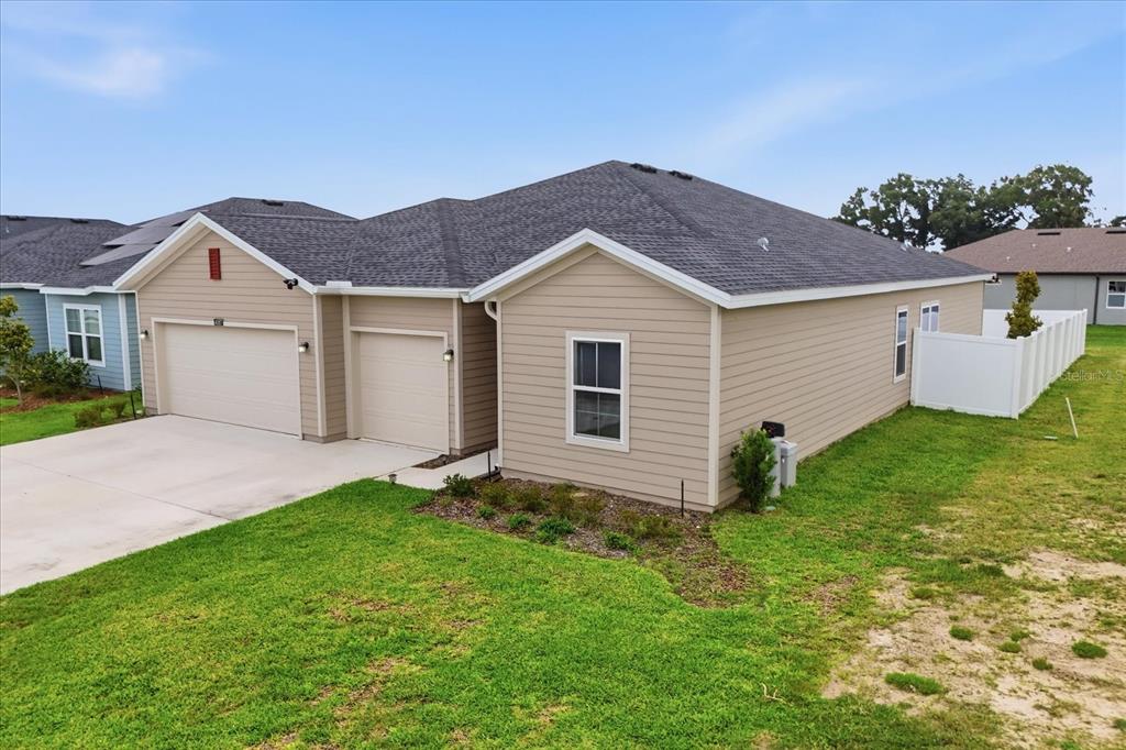 An exterior view of a tan, single-story house with a three-car garage and lawn — 4587 SW 83RD LOOP, OCALA, FL