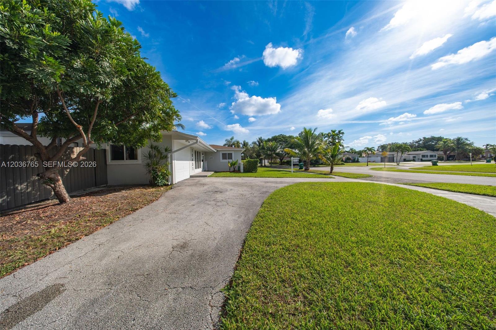 A single-story house with a paved driveway, green lawn, and trees under a blue sky — 10431 SW 93rd St, Miami FL 33176, MIAMI, FL