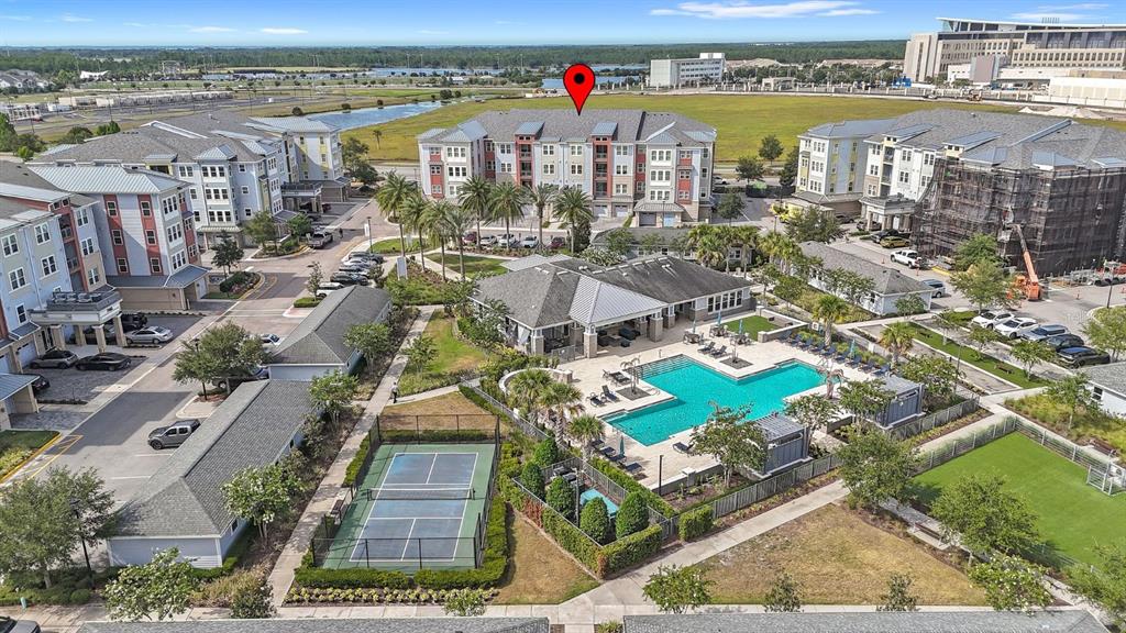 An aerial view shows an apartment complex with a swimming pool, tennis court, and parking — 7505 LAUREATE BOULEVARD UNIT 2206, ORLANDO, FL