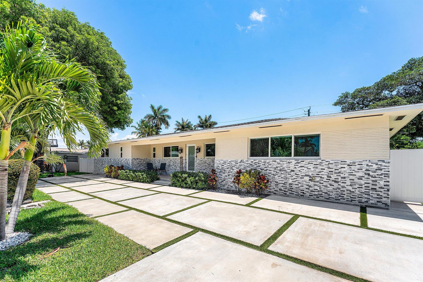 A single-story house with a white brick facade, stone veneer base, and a grid-pattern driveway — 214 SE 5th Street, Dania Beach FL 33004, DANIA BEACH, FL