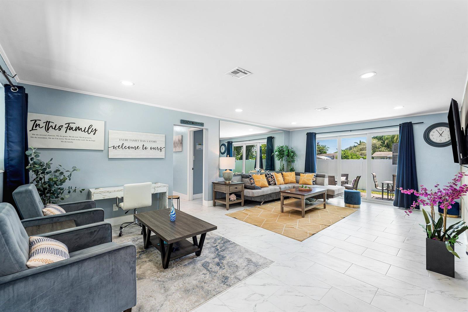 A spacious living room features light blue walls, tile flooring, a sectional sofa, and armchairs — 214 SE 5th Street, Dania Beach FL 33004, DANIA BEACH, FL