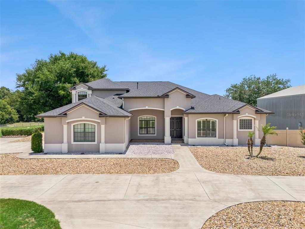 A single-story house with a beige stucco exterior, a gray shingled roof, and a concrete driveway — 19850 SUGARLOAF MOUNTAIN ROAD, CLERMONT, FL