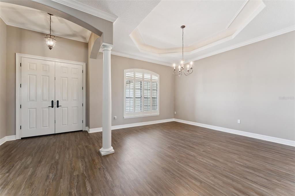An empty room with wood-look flooring, a tray ceiling, a chandelier, and double entry doors — 19850 SUGARLOAF MOUNTAIN ROAD, CLERMONT, FL