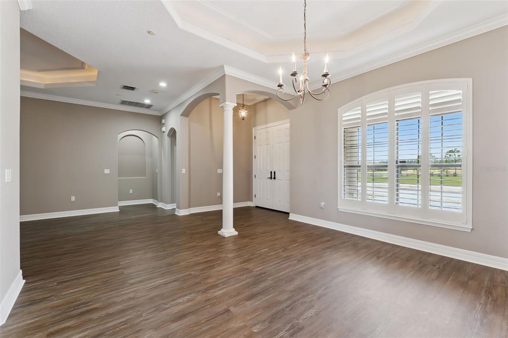 A bright dining room with wood-look flooring, a tray ceiling, chandelier, and arched entryways — 19850 SUGARLOAF MOUNTAIN ROAD, CLERMONT, FL