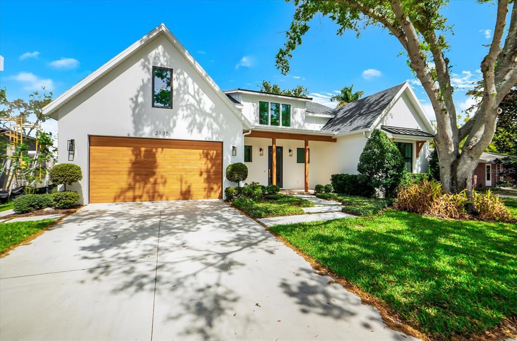 A white house with a wood-paneled garage door and a covered front entryway — 2135 DATURA STREET, SARASOTA, FL