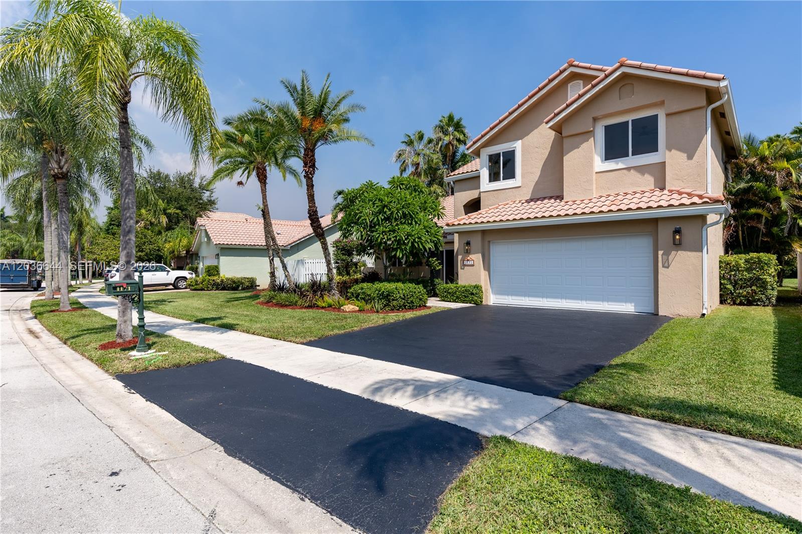 A two-story tan house with a white garage door and a paved driveway — 1171 Laguna Springs Dr, Weston FL 33326, WESTON, FL