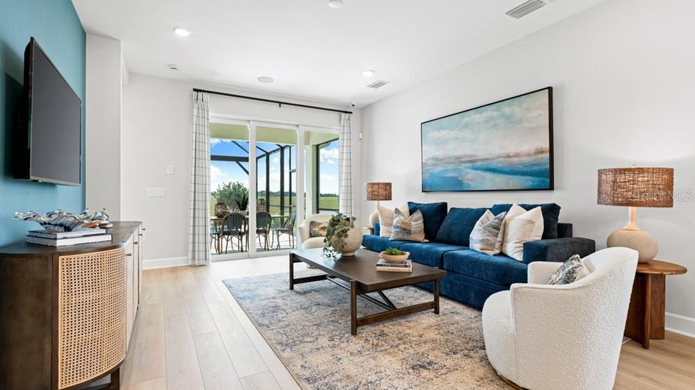 A living room features a blue sofa, a white armchair, and a view of a patio — 26613 DOVE DRIVE, PUNTA GORDA, FL