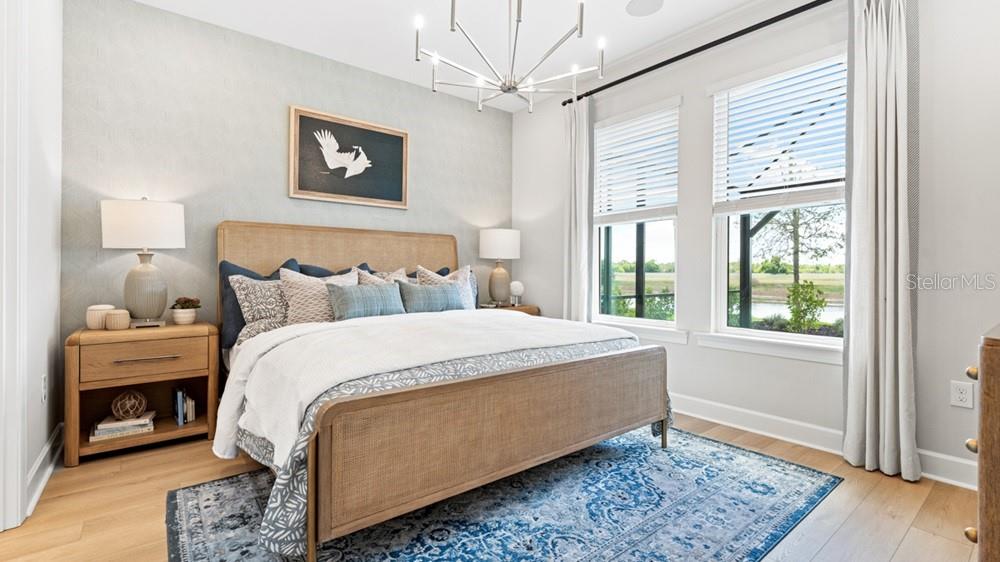 A bedroom features a cane bed, blue patterned rug, and large windows overlooking a landscape — 26613 DOVE DRIVE, PUNTA GORDA, FL