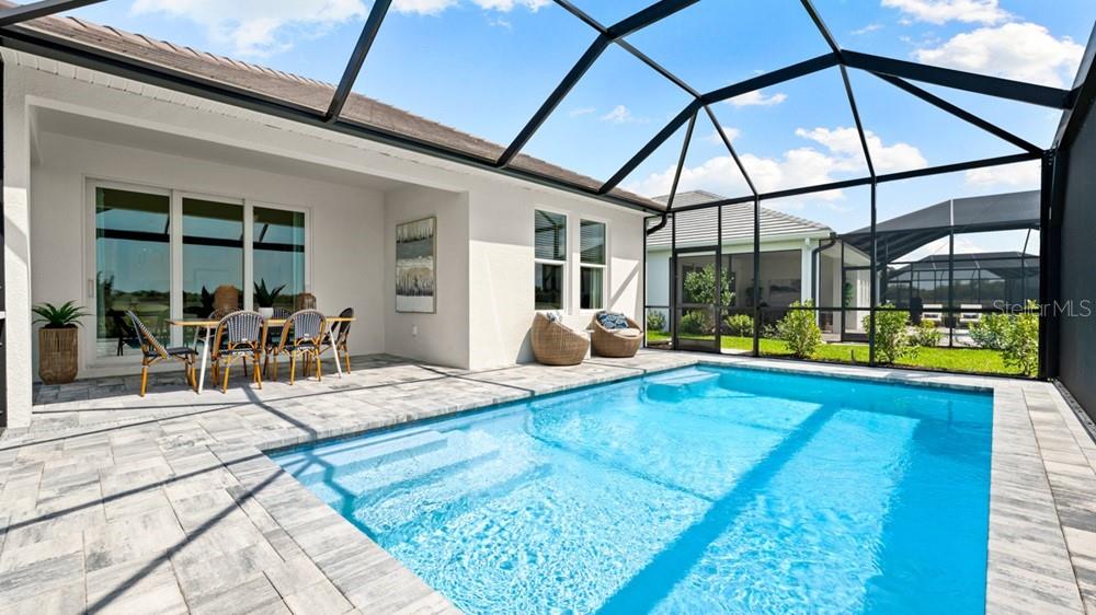 A swimming pool sits on a paved patio enclosed by a screened lanai — 26613 DOVE DRIVE, PUNTA GORDA, FL