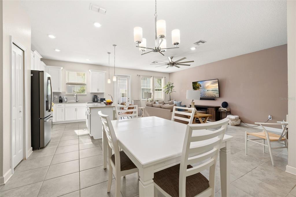An open-concept kitchen and dining area features white cabinetry, tile flooring, and a chandelier — 2905 SATIRE STREET, KISSIMMEE, FL