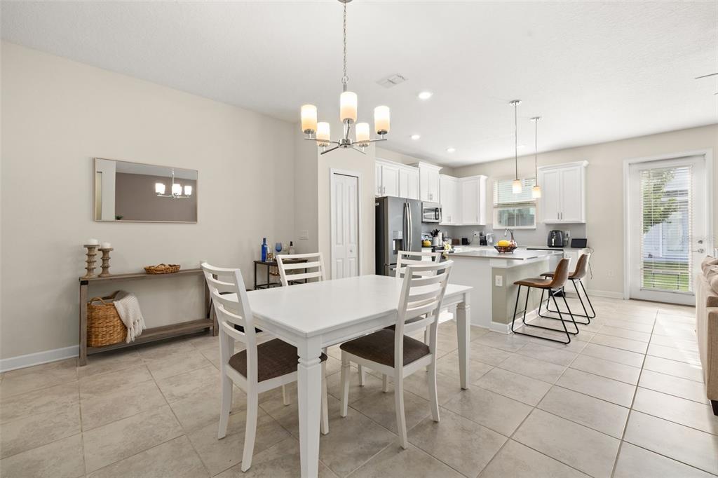 A dining area with a white table and chairs sits adjacent to a modern kitchen — 2905 SATIRE STREET, KISSIMMEE, FL