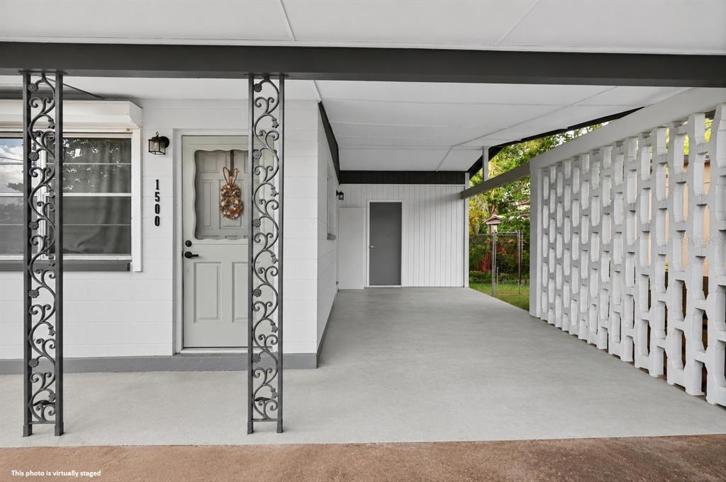 A carport with decorative metal columns and a breeze block wall leads to a front door — 1500 PRIMROSE LANE, DAYTONA BEACH, FL