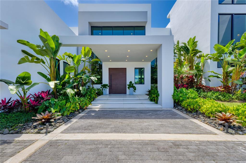 The exterior of a modern white house features a covered entryway with a wooden door — G8 ATLANTIC DRIVE, 7000 BAHIA BEACH BLVD., RIO GRANDE, PR