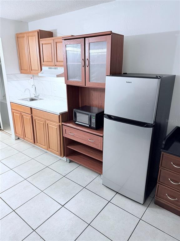 A kitchen features light wood cabinets, a stainless steel refrigerator, and a microwave hutch — 43420 HIGHWAY 27 UNIT 436, DAVENPORT, FL